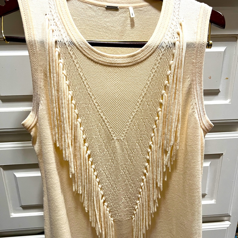 Ivory sleeveless sweater vest with fringe detail.
